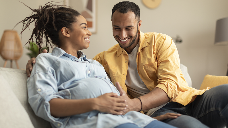 Happy expecting couple relaxing on couch