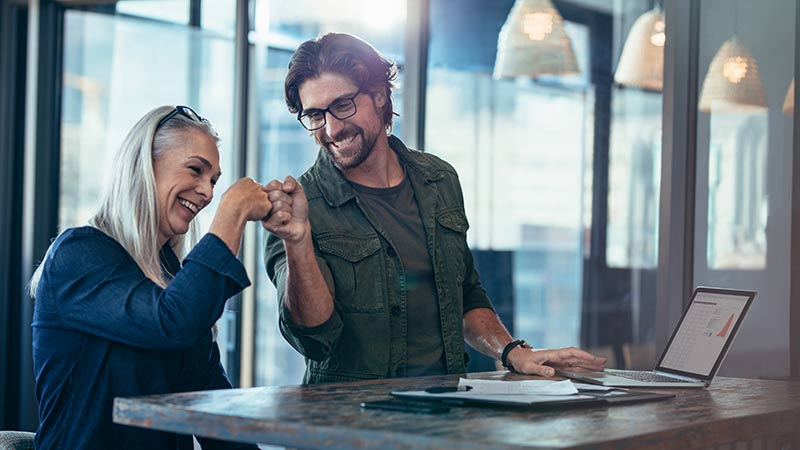 women and man fist bumping in the office
