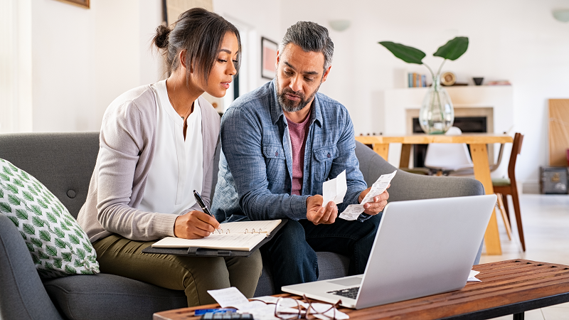Couple sitting in couch doing household accounting
