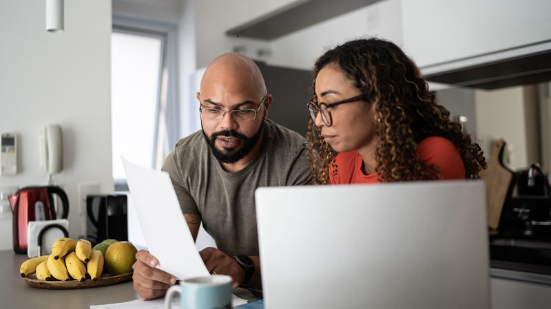 Couple sitting in a kitchen studying a document 