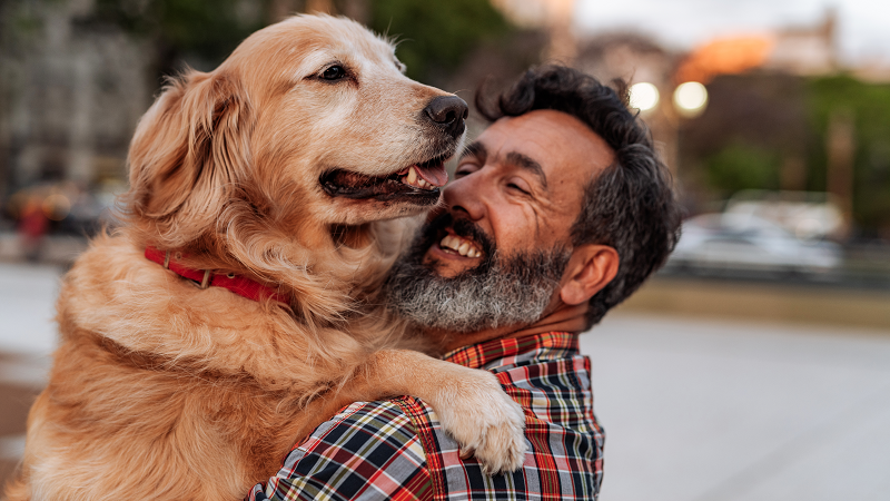 Happy bearded man hugging a Golden Retriever